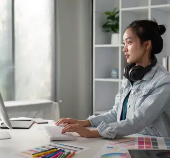 Mulher em frente ao computador digitando no teclado com fone de ouvido no pescoço