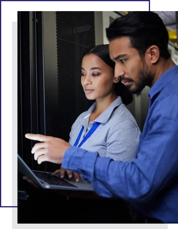 Um mulher em pé, segurando um notebook ao lado de um homem indicando para o notebook